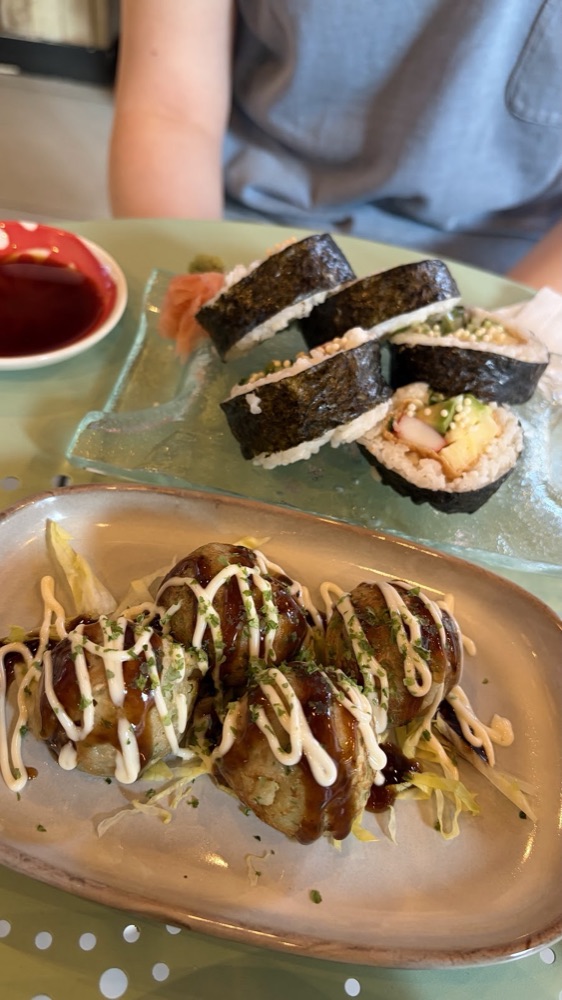 Takoyaki with mayo and aonori beside sushi rolls